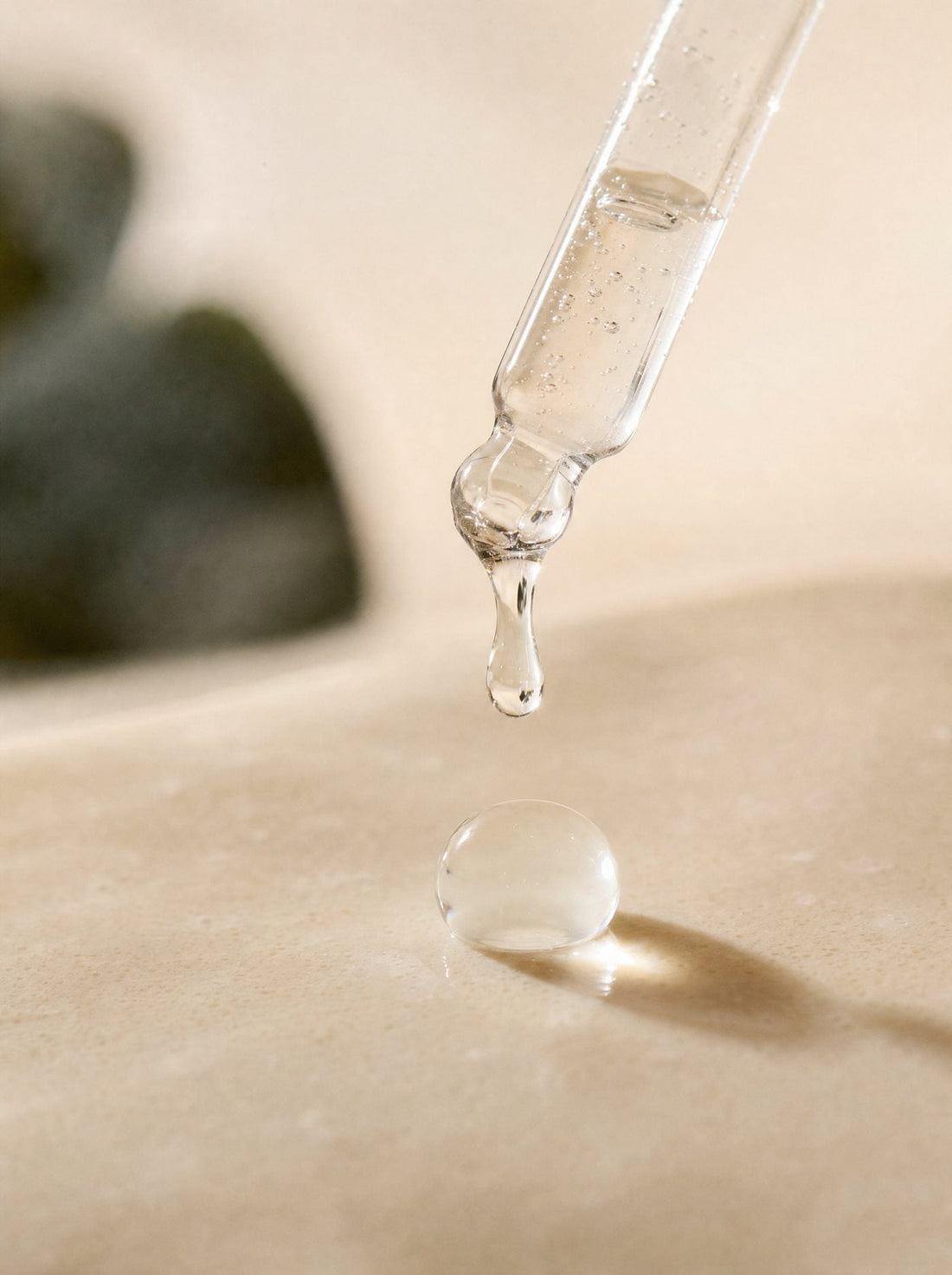 Conta-gotas de vidro liberando uma gota transparente.