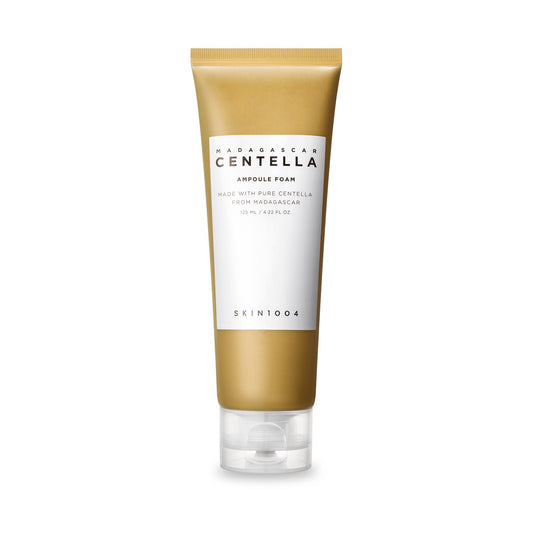 Bisnaga dourada e branca da espuma de limpeza SKIN1004, fundo branco, rótulo frontal legível.