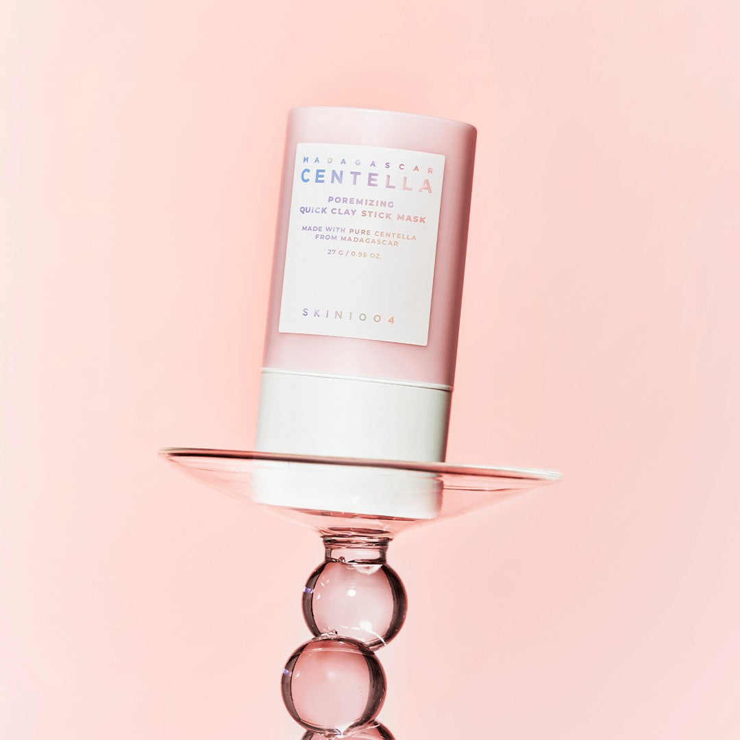 Bastão equilibrado sobre um suporte de vidro rosa, fundo rosa.