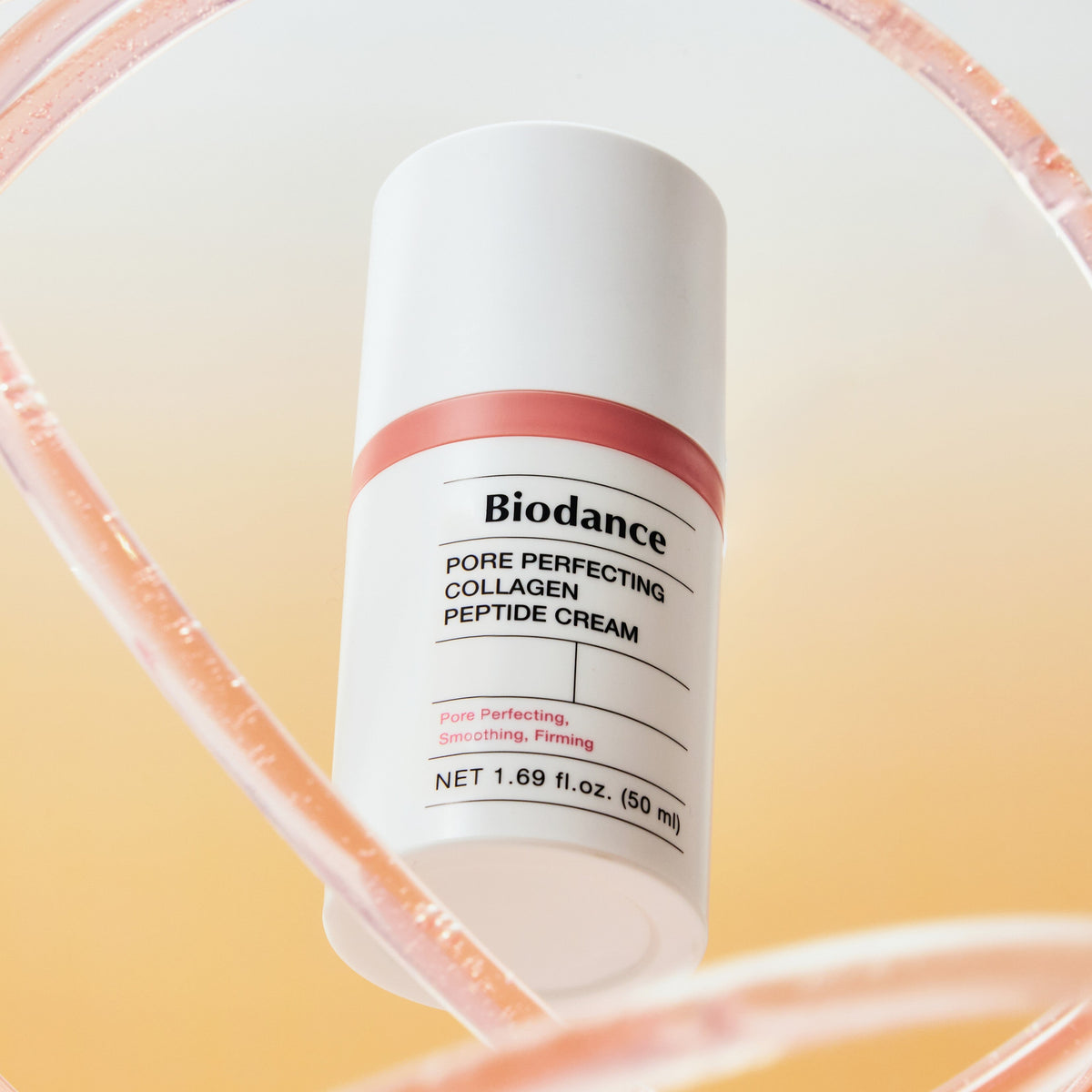 Frasco do creme Biodance visto de perto atras de um aro de vidro rosa
