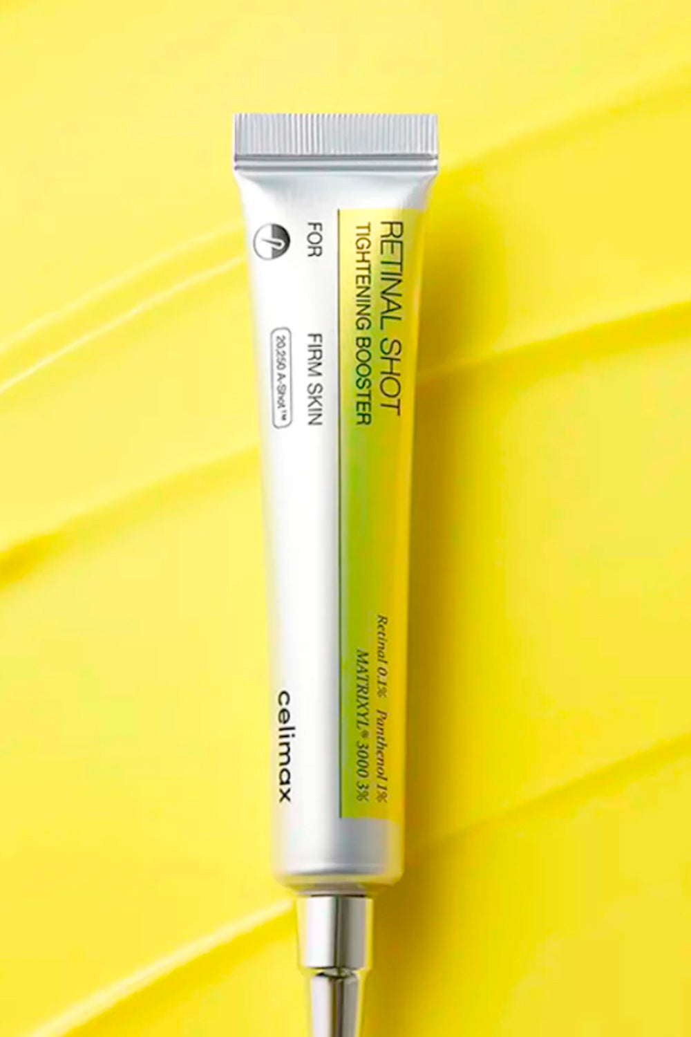 Bisnaga prateada e amarela do Celimax The Vita-A Retinal Shot deitada sobre fundo amarelo.