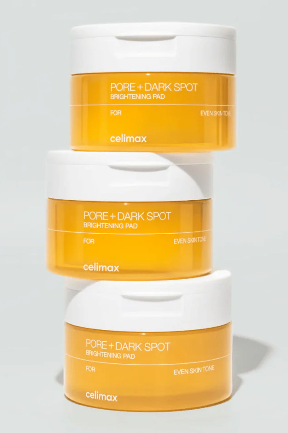 Três potes Celimax Pore + Dark Spot empilhados sobre fundo cinza claro