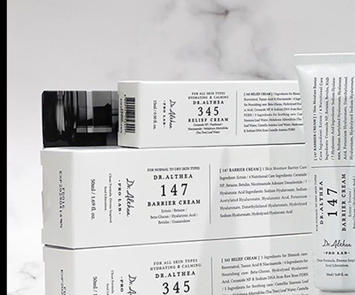 Caixas e bisnagas Dr. Althea 345 Relief Cream e 147 Barrier Cream sobre superfície de mármore branco
