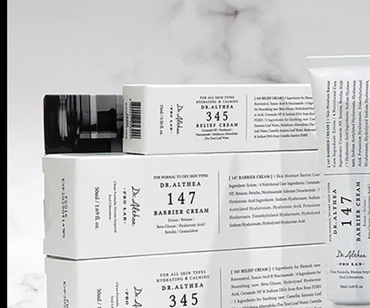 Caixas e bisnagas Dr. Althea 345 Relief Cream e 147 Barrier Cream sobre superfície de mármore branco